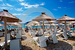 Summer sea coast in the resort town, beach with sun loungers and umbrellas, blue sunny sky, background of travel during vacation