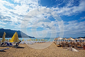 Summer sea coast in the resort town, beach with sun loungers and umbrellas, blue sunny sky, background of travel during vacation