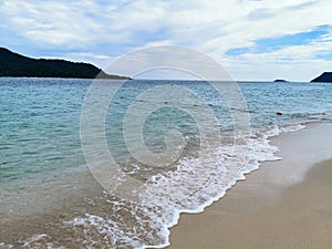 Summer sea view from tropical beach with sunny sky and mountain Island. Nice sand beach and wave in sea.