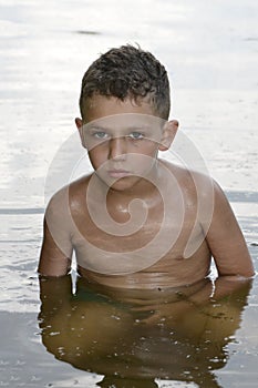 In the summer of serious curly-haired boy is bathed in the rive