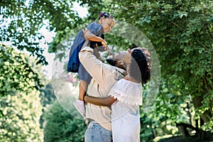 Summer shot of happy african family playing in the park. Family portrait with happy people smiling at the park, father