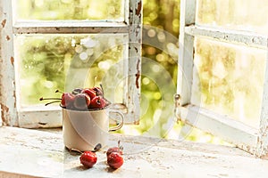 Summer simple still life. Sweet cherry in an iron mug on the old window overlooking the garden. Vintage style. summer on the farm.