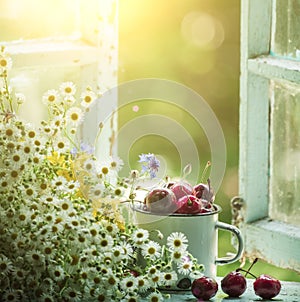 Summer simple still life. Sweet cherry in an iron mug on the old window overlooking the garden. Vintage style. summer on the farm.