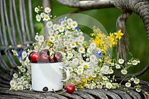 Summer simple still life. Sweet cherry in an iron mug and a simple bouquet of summer field flowers. Vintage style. summer on the f