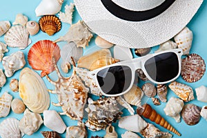 Summer skin care cosmetics, panama and sunglasses on blue background.