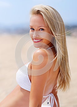 Summer smiles and sunny days. A sun kissed woman relaxing on the beach in a bikini.