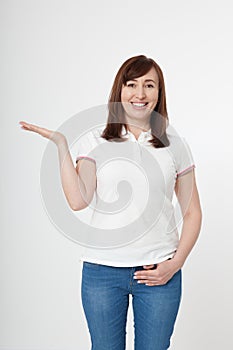 Summer. Smiling beautiful woman wearing blank template white t shirt showing something by hand, mock up on white background