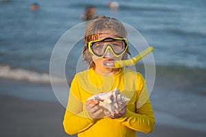 Summer snorkeling with kids. Beach vacation. Fun kid wearing a snorkel scuba mask found coral or shell in ocean water