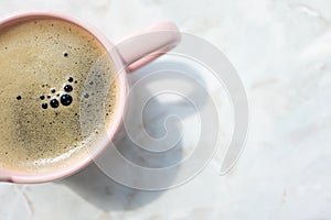 Summer soft drink with bubbles foam in pink cup on marble table background with copy space, top view. Minimalist lifestyle