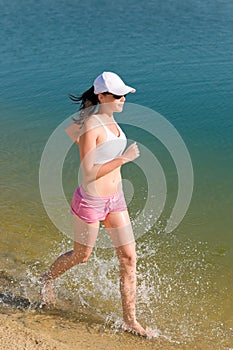 Summer sport fit woman jogging along seashore