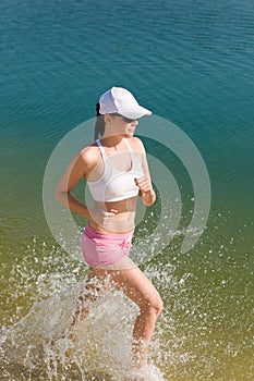 Summer sport fit woman jogging along seashore