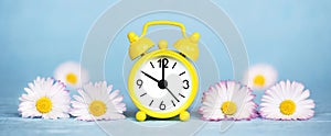 Summer, spring concept, alarm clock and daisy flowers on blue background, web banner