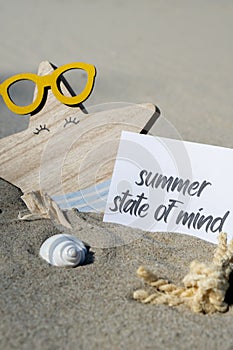 SUMMER STATE OF MIND text on paper greeting card on background of funny starfish in glasses summer vacation decor. Sandy