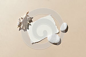 Summer stationery sunlight flat lay. Mock up empty paper blank card with sea shells and pebbles on beige background.