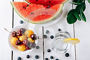 Summer still life of fresh fruit and berries on a white wooden surface