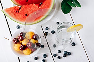 Summer still life of fresh fruit and berries on a white wooden surface