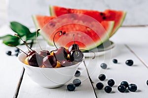 Summer still life of fresh fruit and berries on a white wooden surface