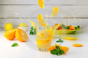 Summer still life with Orange juice splash and mint on white background. Healthy lifestyle
