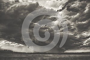 Summer storm cyclone over field hills and forest. Big spooky scary heavy rainy cloud over the valley black and white photography