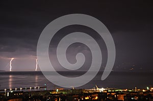 Summer storm over Adriatic Sea with two thunderstorm and city of Rijeka by night