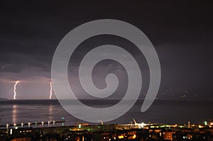 Summer storm over Adriatic Sea with two thunderstorm and city of Rijeka by night photo