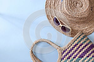 Summer straw hat beach, sunglasses and bag on light blue background. Copy space. Top view