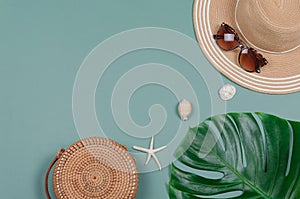 Summer straw hat, tropical monstera leaf, sunglasses, shells, starfish on green background