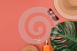 Summer straw hat, tropical monstera leaf, sunglasses, shells, suncream, starfish on red background