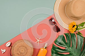 Summer straw hat, tropical monstera leaf, sunglasses, shells, suncream, starfish on red background