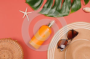 Summer straw hat, tropical monstera leaf, sunglasses, shells, suncream, starfish on red background