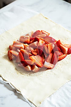 Summer strawberry galette with almond flakes in making. Food preparation concept