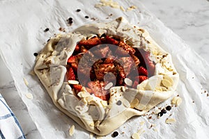 Summer strawberry galette with almond flakes in making. Food preparation concept