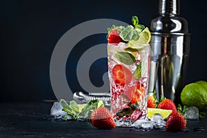 Summer strawberry mojito cocktail with lime, white rum, soda, cane sugar, mint, and ice in glass on deep blue background. Cold