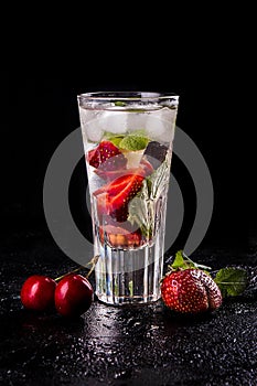 Summer strawberry sweet cherry cocktail ice cold drink in glasses on black background