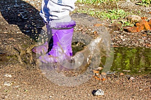 summer stroll kid in rubber boots in a puddle.