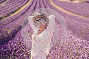 Summer style portrait of cute middle age woman smiling and having fun with violet flowers of lavender fields in background -