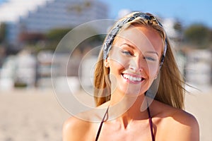 Summer sun and happy smiles. A sun kissed woman relaxing on the beach in a bikini.