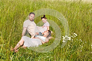 Summer sunny day for a young family, dad, mom and little girl became joyful and happy. Beautiful flower meadow, happy