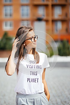 Summer sunny lifestyle fashion portrait of young stylish hipster woman walking on street, wearing cute trendy outfit