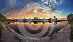 Summer sunset in the city. Reflection on the river.