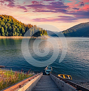 Summer sunset on Dragan lake with staircase and fishing boat.