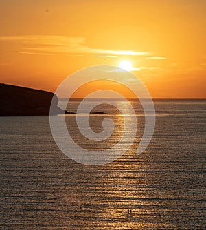 Summer sunset over Greek island, Cyclades, Greece. Golden sun colors the sky and makes sea sparkle