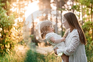 Summer sunset in the park or forest. Baby daughter on a piggy back ride with her mother.