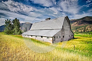 Summer sunset with a red barn in rural Montana and Rocky Mountains