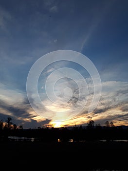 Summer sunset sky with clouds river and forest