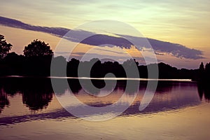 Summer sunset, woodland and reflections in the lake