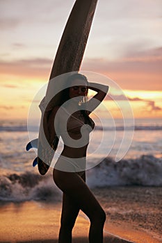 Summer. Surfer girl silhouette with surf board on sunset beach
