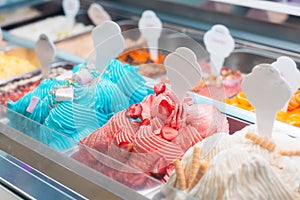 Summer sweet in italian gelateria. Close up of colourful delicious ice cream in trays in showcase fridge at