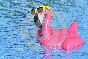 Summer Swimming Pool Inflantable Rubber Pink Flamingo Toy with Yellow Sunglasses in Clean Pool or Sea Blue Water. 3d Rendering