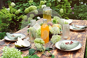 Summer table set. Dining table decorated fresh flowers and fruits outdoor.
